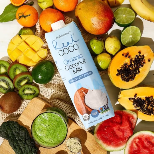Flat lay photograph of Real Coco Organic Coconut Milk on top of an assortment of fruit.
